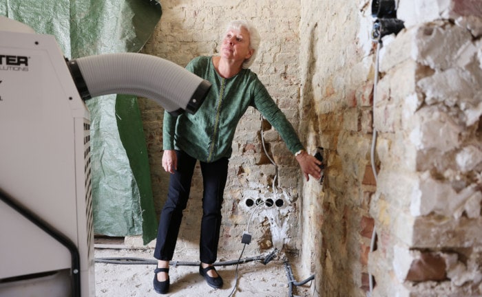 Eine Hausbesitzerin in Erftstadt-Blessem zeigt Flutschäden an den Häuserwänden: Das Tief Bernd verursachte Schäden in Höhe von 8,2 Milliarden Euro