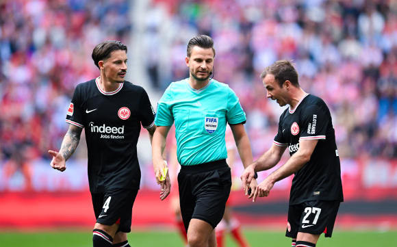 Die Fußballspieler Robin Koch und Mario Götze von Eintracht Frankfurt beschweren sich bei dem Schiedsrichter Daniel Schlager: Beschwerden reichen Kunden bei ihrem Versicherer oftmals online ein (Foto: picture alliance / DeFodi Images | Silas Schueller)