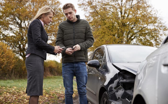 Eine Frau und ein Mann unterhalten sich nach einem Verkehrsunfall: Der GDV hat die Typklassen für die KFZ-Haftpflicht erneuert.