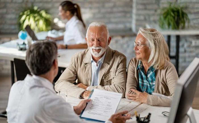 Versicherungsmakler bespricht mit einem Ehepaar deren Lebensversicherung: Lebensversicherer stehen 2023 besser da als im Vorjahr.