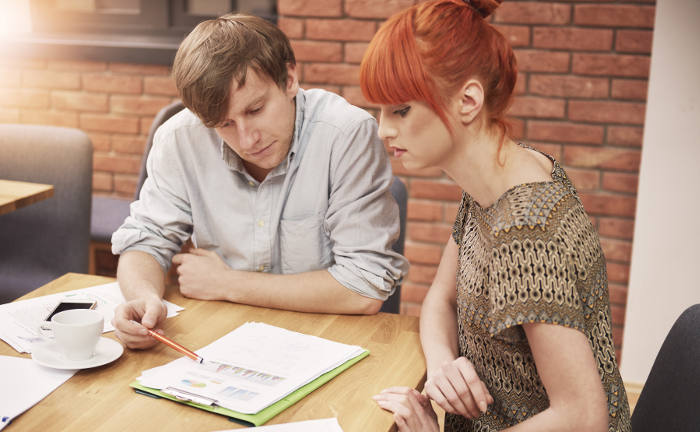 Ein Mann und eine Frau schauen sich Unterlagen an: Altersvorsorgefehler können Versicherte im Ruhestand viel Geld kosten.