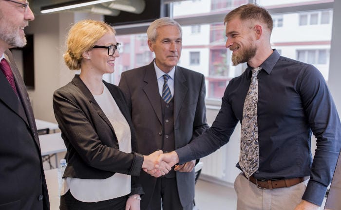 Chefin schüttelt jungem Mitarbeiter die Hand: Ein gutes bAV-Angebot nutzen Mittelständler um junge Mitarbeiter zu binden.