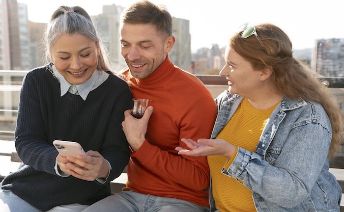 Drei Personen schauen auf ein Smartphone: Über Online-Kampagnen erreichen Makler ihre Zielgruppen.