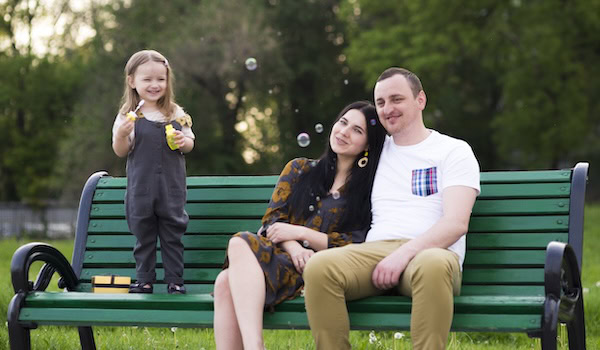 Junge Familie sitzt auf Parkbank Foto: Freepik