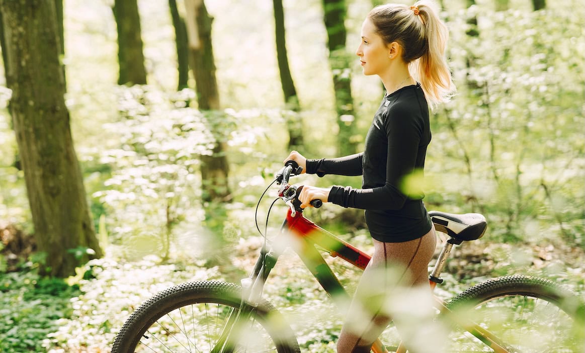 Frau schiebt ihr Fahrrad durch den Wald: Im Jahr 2024 mussten Versicherer 160 Millionen Euro für Fahrraddiebstahl in die Hand nehmen, ein Rekordwert.