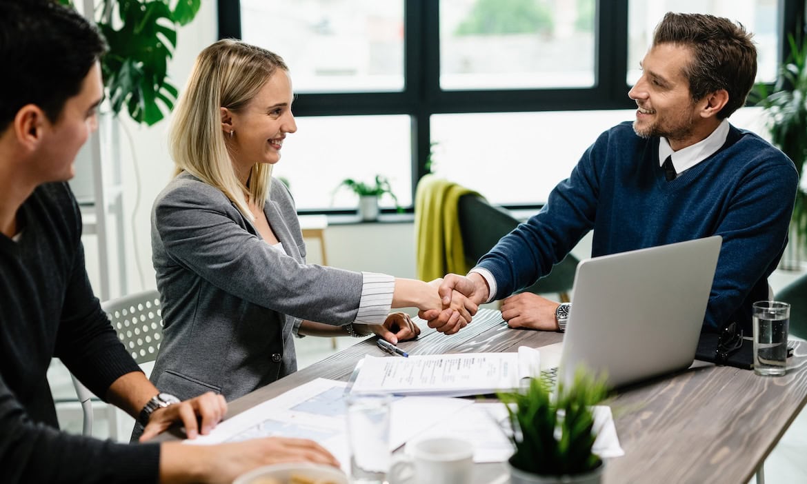 Versicherungsmakler gibt Kundin die Hand: Um ausländische Fachkräfte gut zu beraten, sind Englischkenntnisse hilfreich.