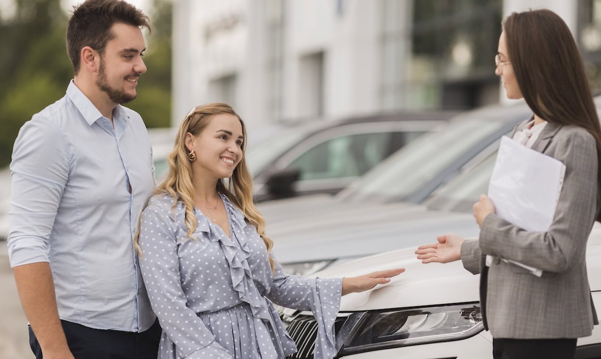 Paar spricht mit Autohändlerin: Angestellte in Möbel- und Elektromärkten sowie Autohäusern müssen nach Paragraf 34k keine Sachkundeprüfung ablegen, anders als Versicherungsvermittler.