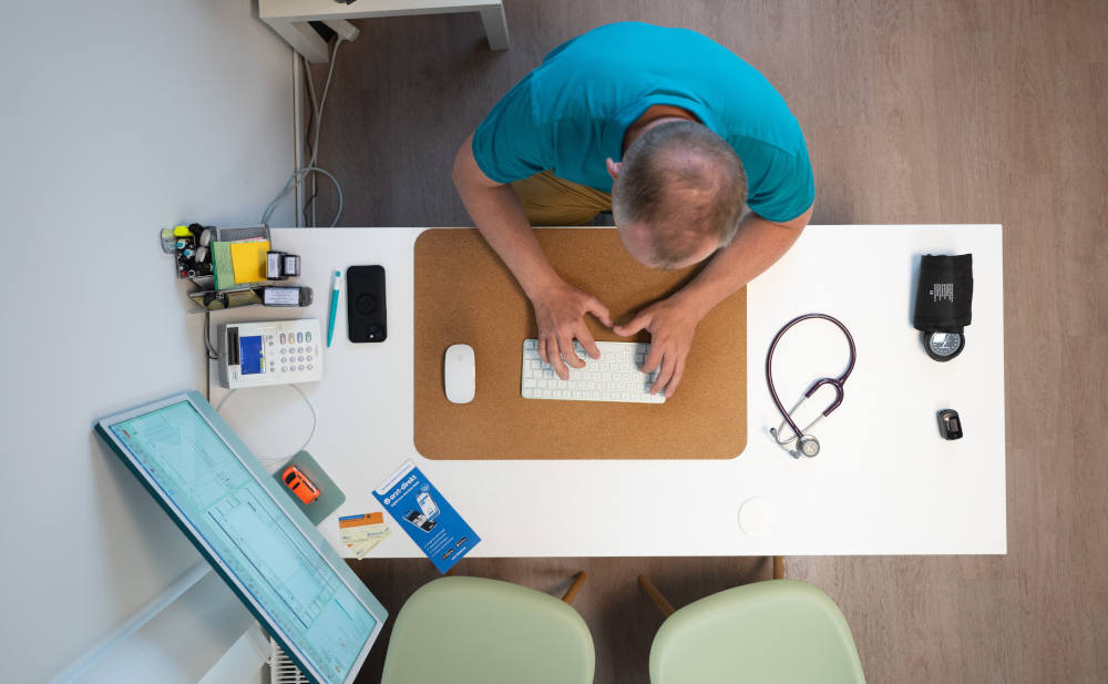 Hausarzt im Sprechzimmer seiner Praxis: Betriebshaftpflichtversicherung für Ärzte abgefragt