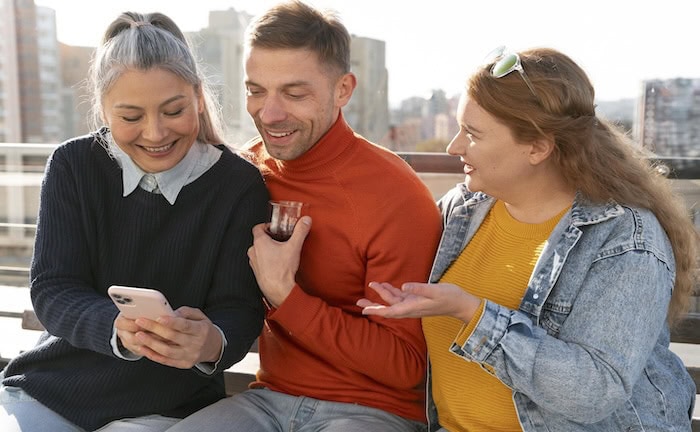 Drei Personen schauen auf ein Smartphone: Über Online-Kampagnen erreichen Makler ihre Zielgruppen.