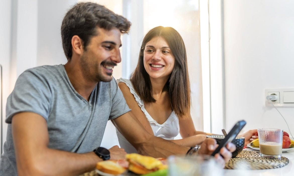 Junge Mann und Frau mit Smartphone: Jeder fünfte junge Mensch informiert sich überwiegend in den sozialen Medien über Finanzen.