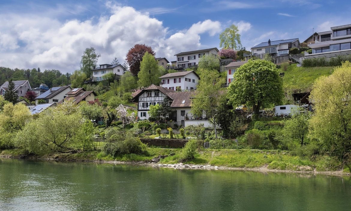 Eine Wohnsiedlung in Flußnähe: Tarife für Wohngebäudeversicherungen unterscheiden sich immer mehr bei Qualität und Preis.