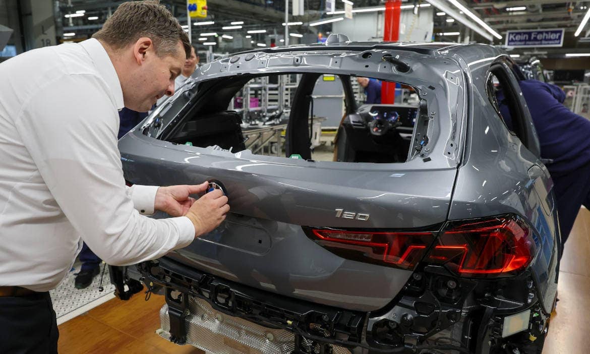 Sven Schulze (CDU), Wirtschaftsminister von Sachsen-Anhalt, klebt das BMW-Logo auf einen Wagen im BMW-Werk Leipzig: Der Designschutz für sichtbare Autoteile treibt die Kosten in der KFZ-Versicherung