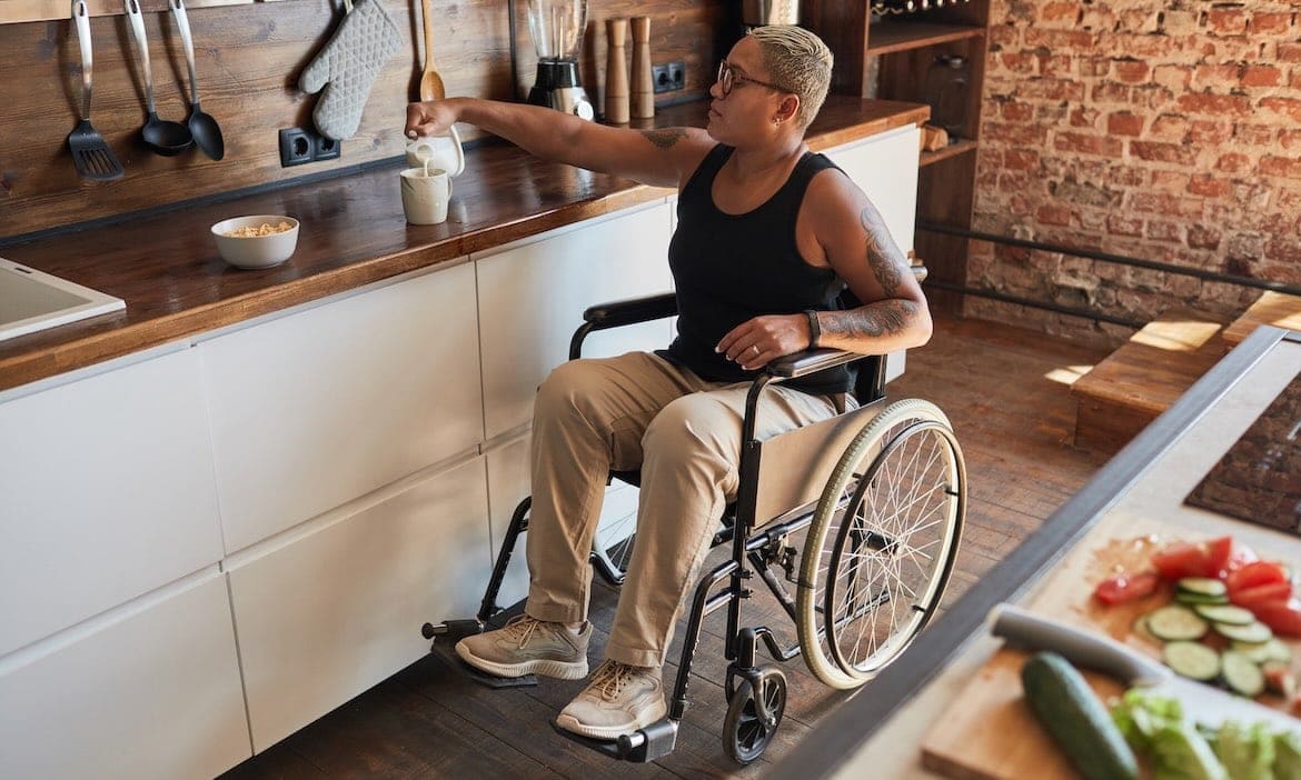 Eine Frau, die auf einen Rollstuhl angewiesen ist, macht sich etwas zu essen: Fünf BU-Versicherer haben sich dem BU-Unternehmensrating von Franke und Bornberg gestellt